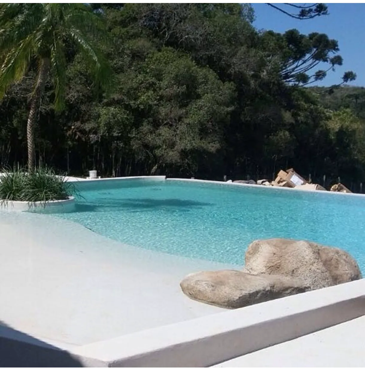 Piscina de praia com água turquesa e borda em areia